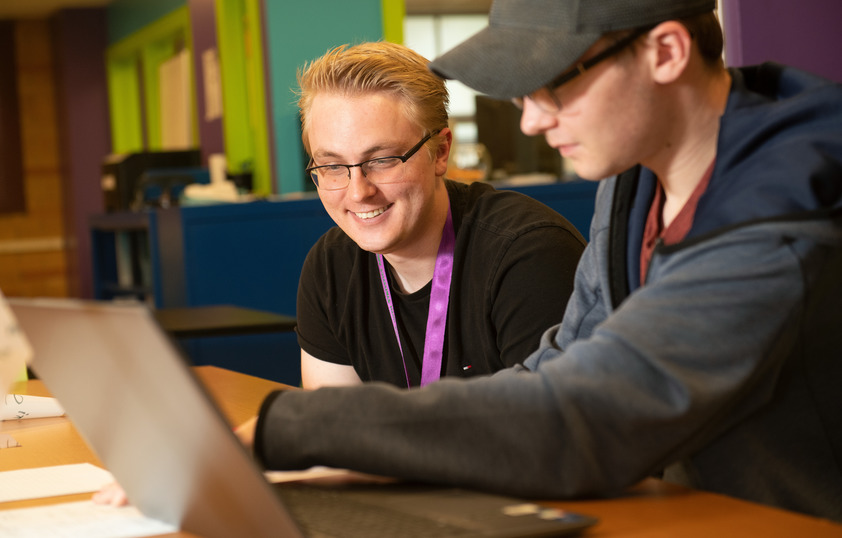 Two students work together on a laptop