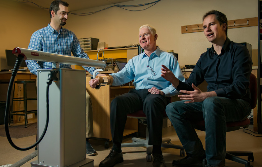 Two researchers walk paitent through electrical engineering test in lab