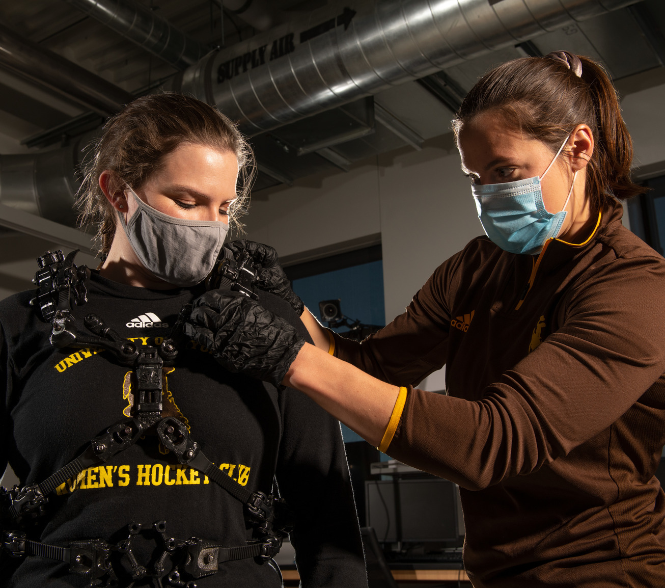 An electrical engineer assists athlete into electrical body suit