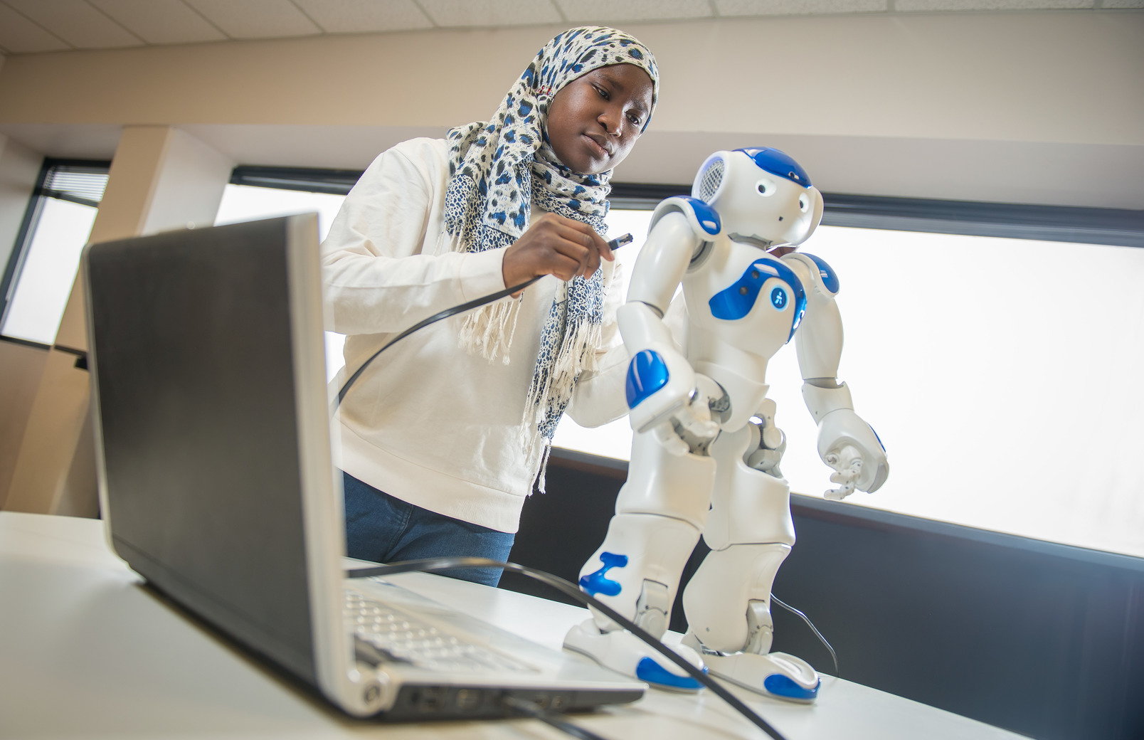 A student plugs in a robot to a laptop