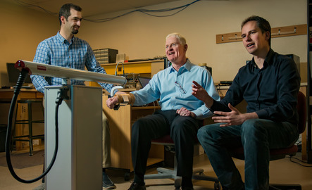 Two researchers walk paitent through an electrical engineering test in lab
