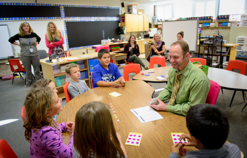 Teacher sitting at desk with students