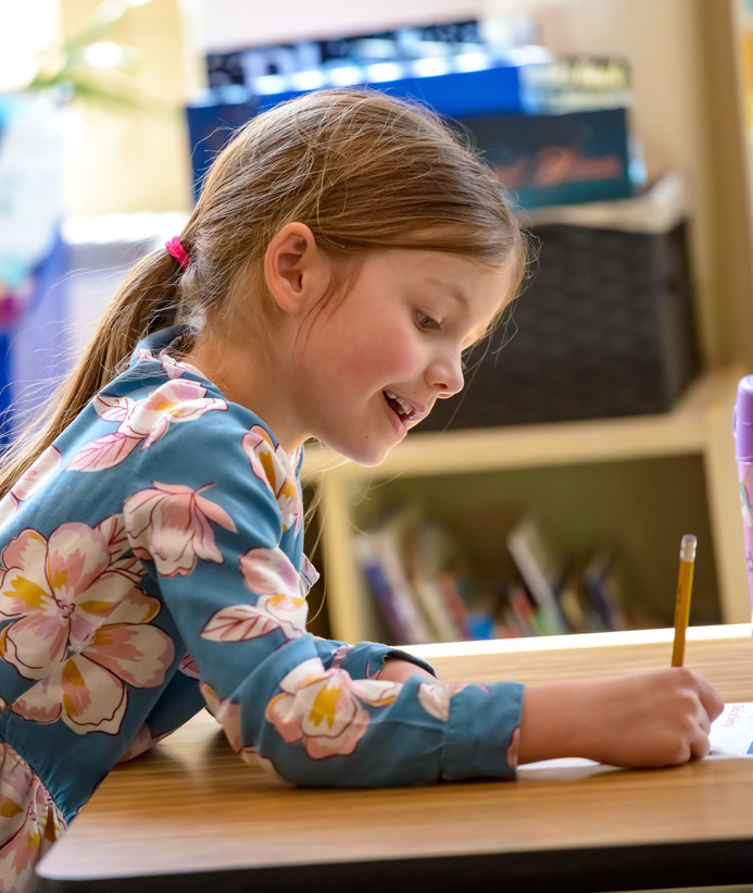 An elementary aged student writes at her desk