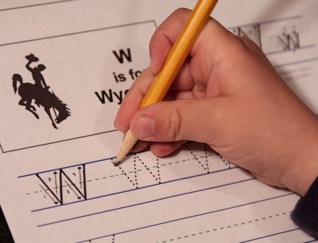 Child writing "W's" on a worksheet