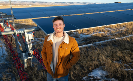 Student poses in front of solar panels