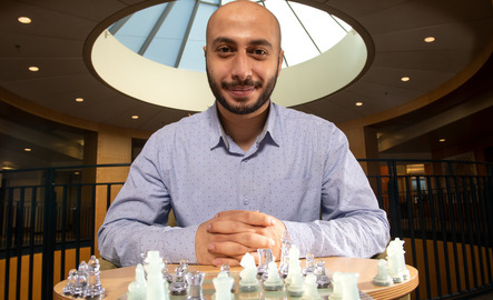 A student smiles with a chess board