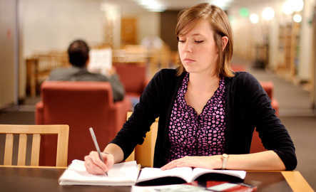 Student writing in a library