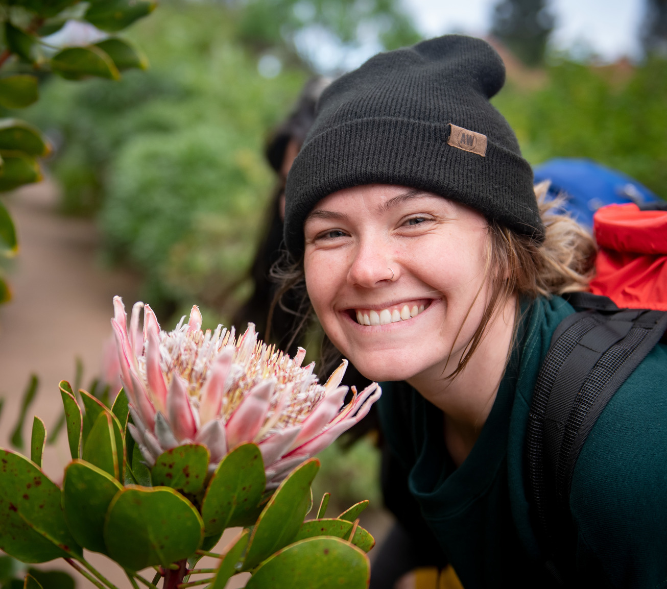 A student smiles for a picture next to a large flower
