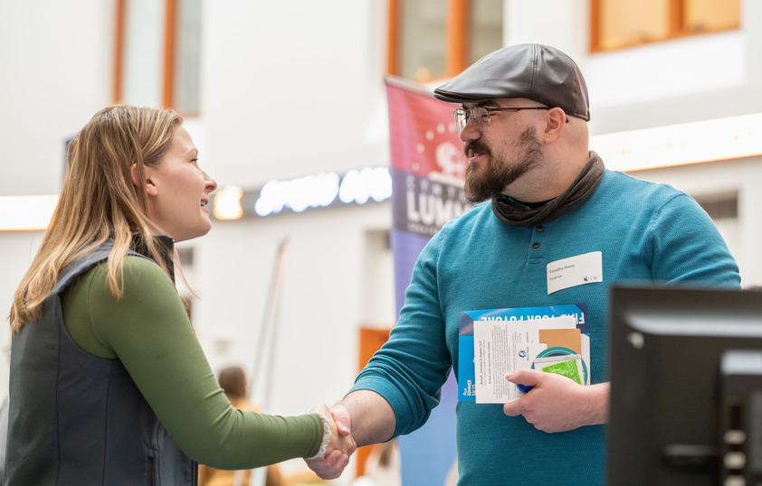 A student shakes an employer's hand at a job fair