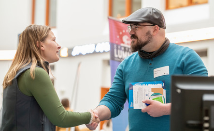 A student and a vendor shake hands during a career fair