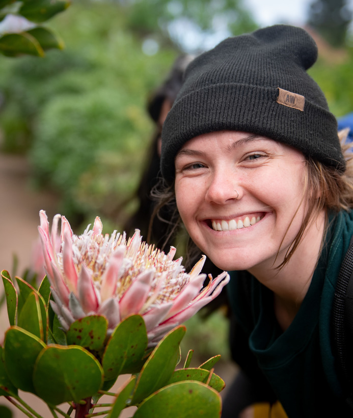 A student smiles for a picture next to a large flower