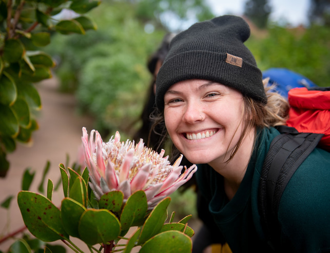 A student smiles for a picture next to a large flower