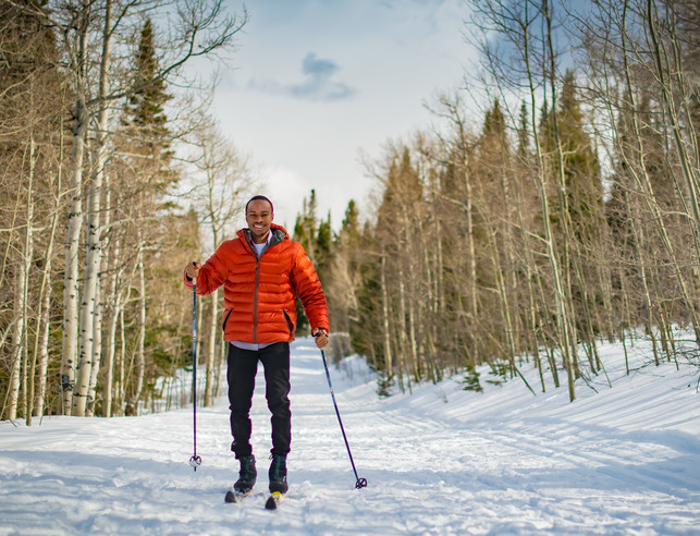 A student smiles for a photo while cross country skiing