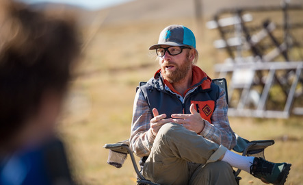 A professor talks to a group of people in a lawn chair