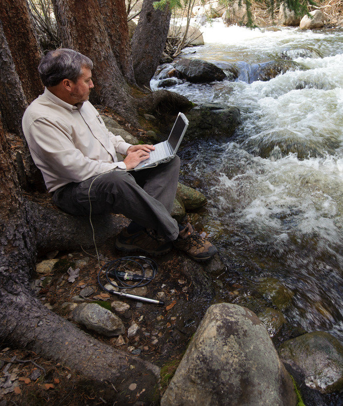 Researcher with laptop next to a river
