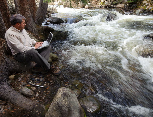 Researcher with laptop next to a river