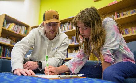 A university student helps a middle school-aged student with a paper