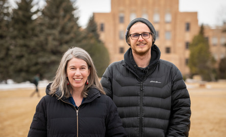 Two faculty members smile for a photo