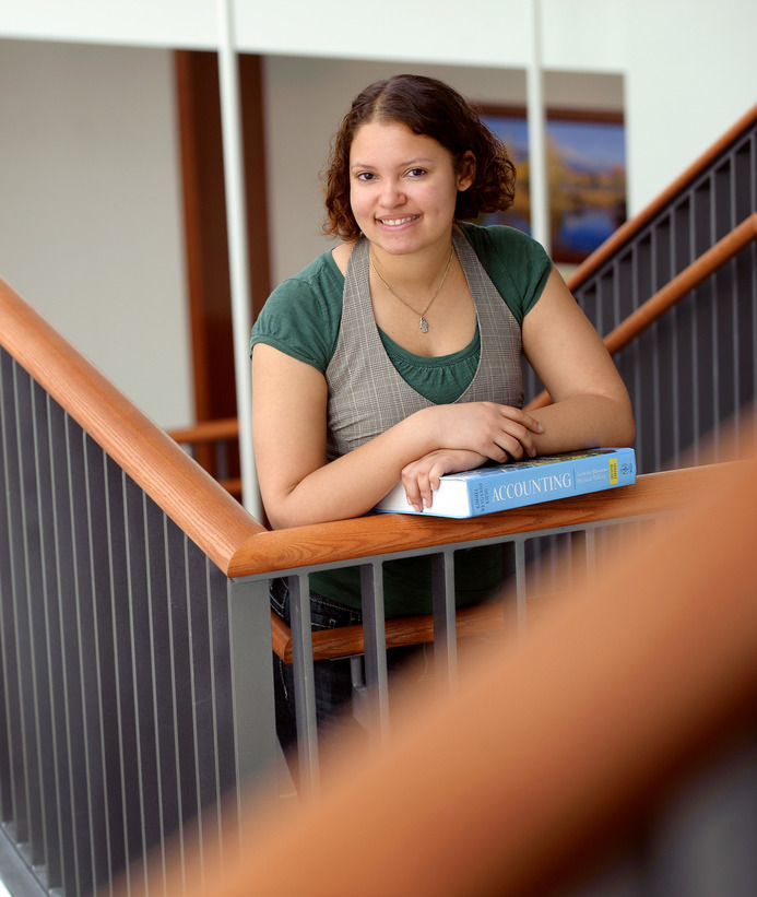 A finance student holds a book in a stairwell