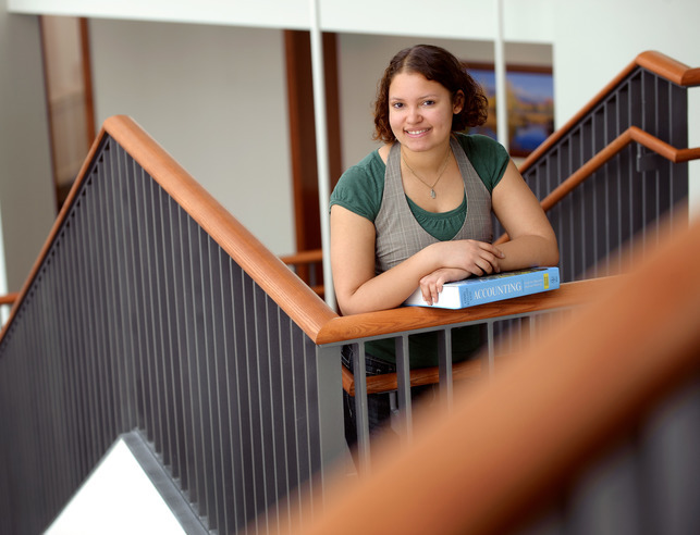 A finance student holds a book in a stairwell
