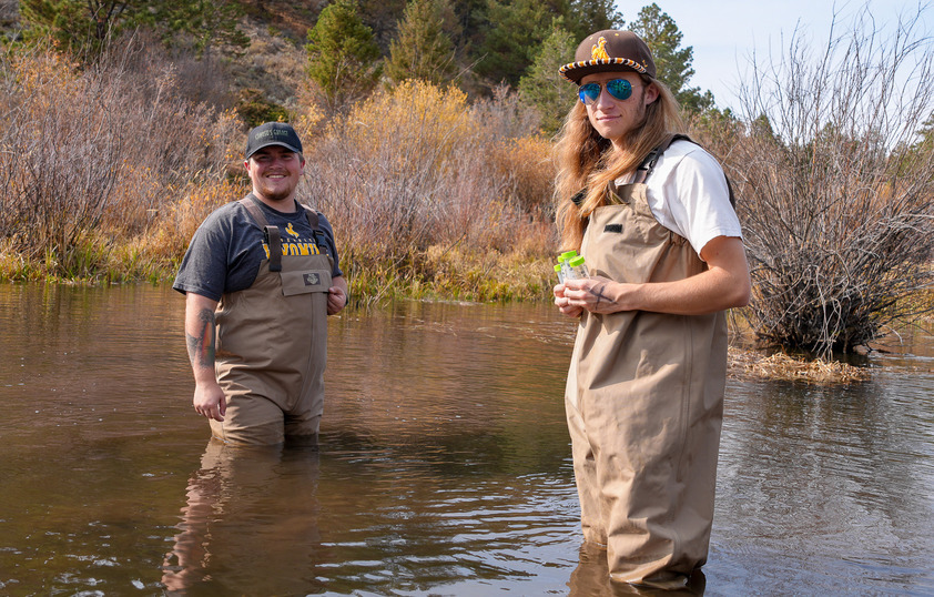 Two students standing in a body of water doing researcher