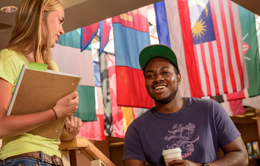 Students talk in the Union with different countries' flags in the background