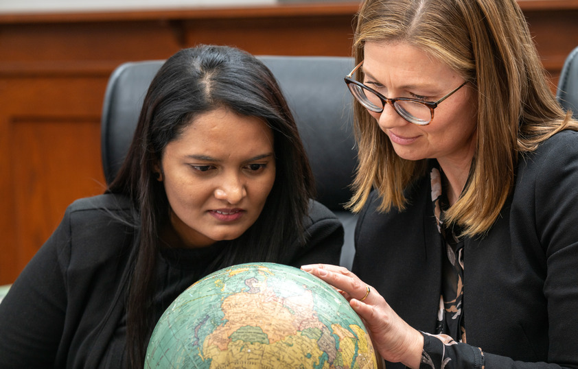 Professor and student look at globe together