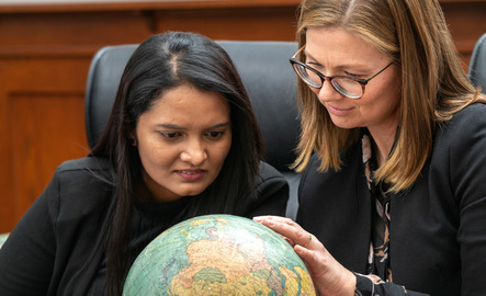 Professor and student look at globe together