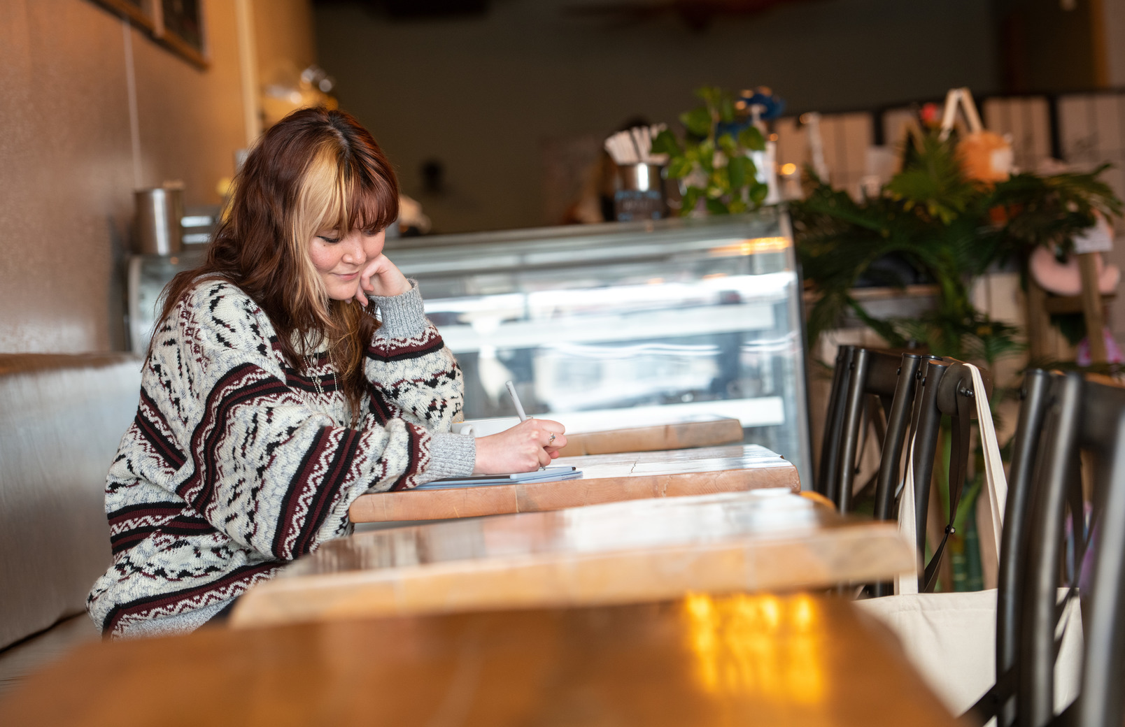 Person writes in a notebook in a coffee shop