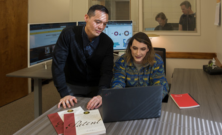 Two people look at a laptop together