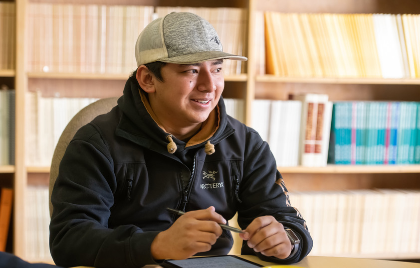 A student with a hat sits in a group discussion.