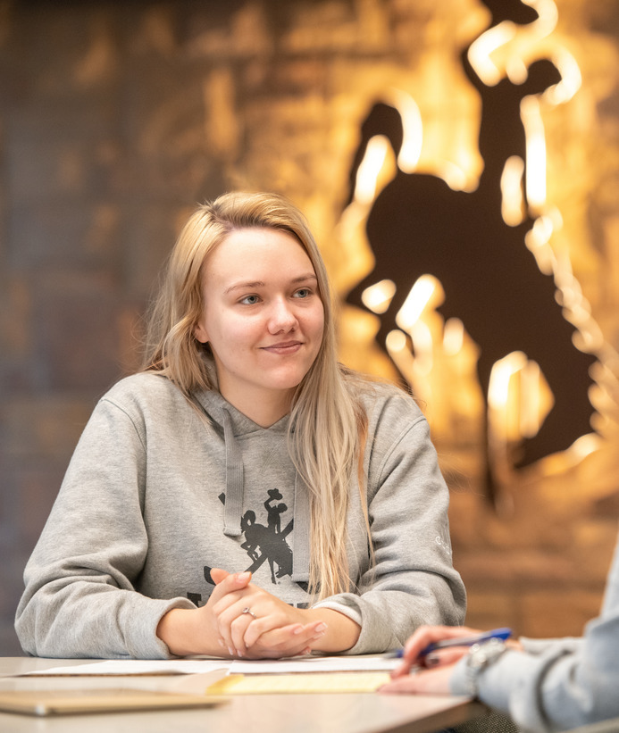 A student sits in front of a backlit UW Steamboat icon logo