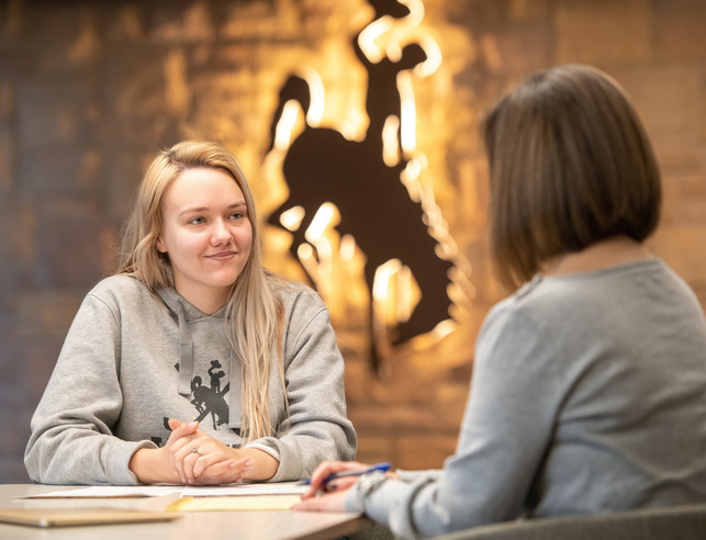 A student sits in front of a backlit UW Steamboat icon logo