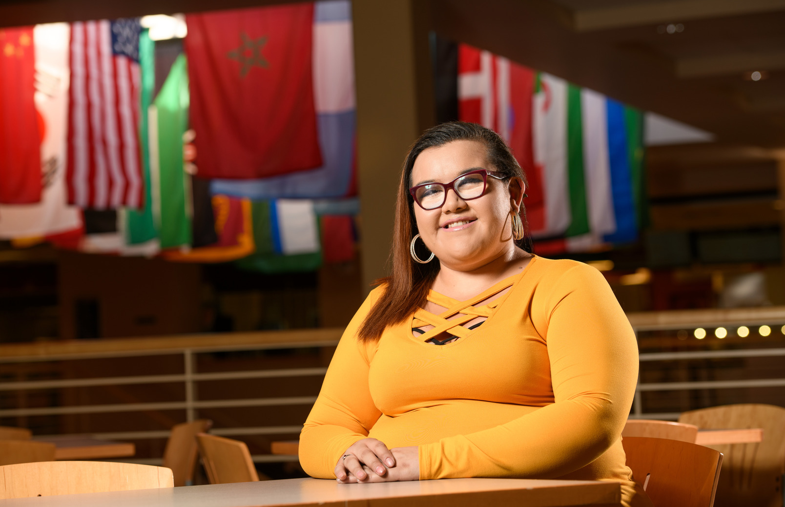 A student in a yellow shirt sits among international flags in the Wyo Union.