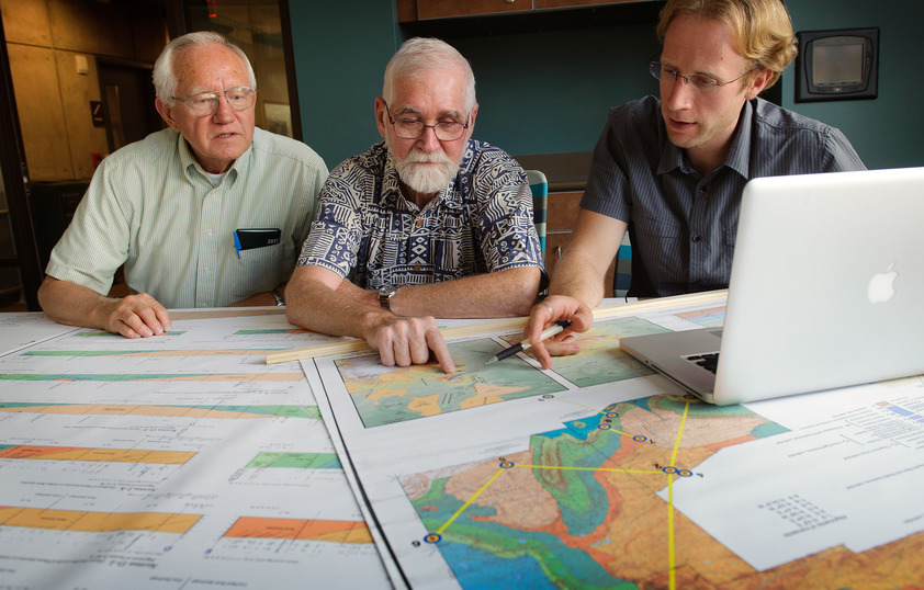 Three people look at multiple maps together