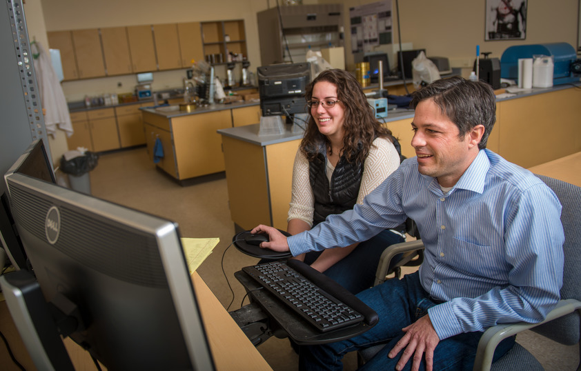 A professor and student work together on a computer.