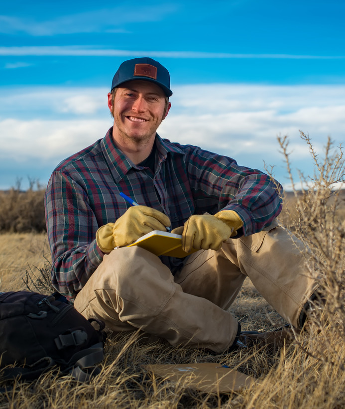 A student smiles for a photo out in the field