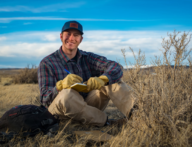 A student smiles for a photo out in the field