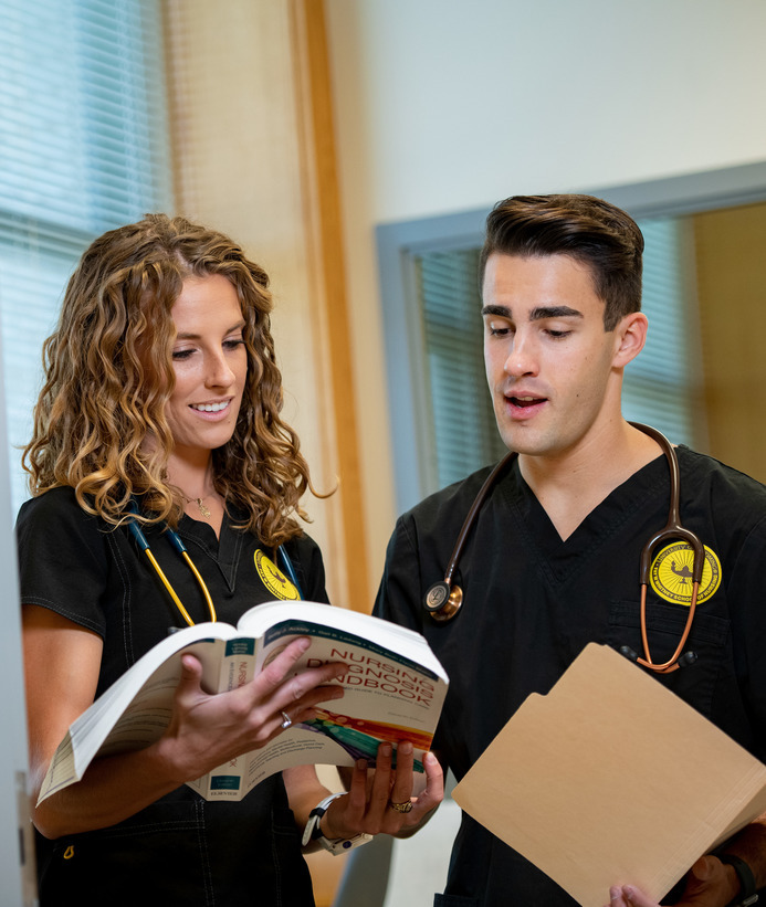 Two nurses read a book together