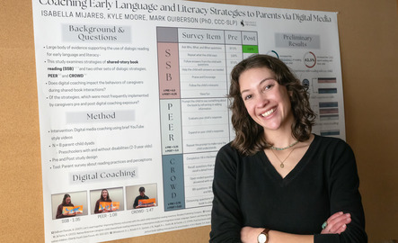 Language specialist stands in front of a poster smiling