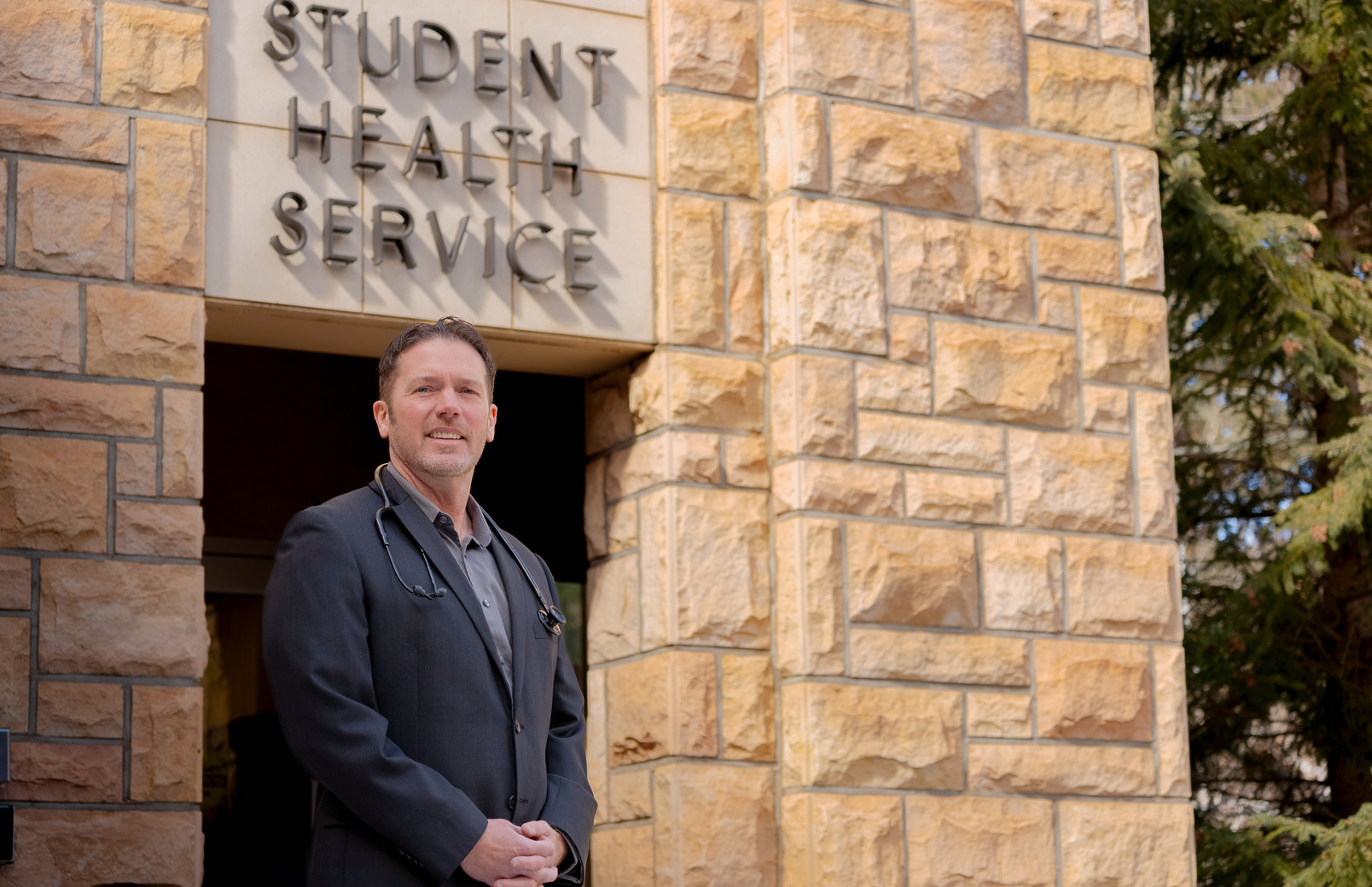 A healthcare worker smiles outside of the Student Health Service building