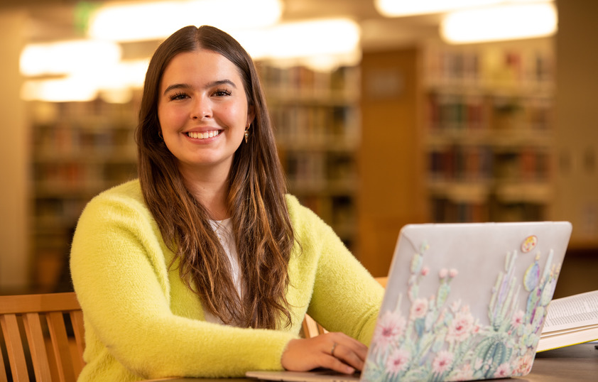 A student works on a laptop in the library
