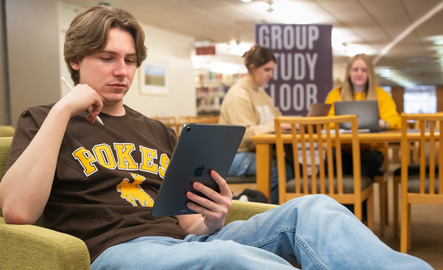 A student studies on their iPad in the library