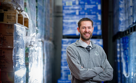 UW hospitality alum standing in front of beverage stock