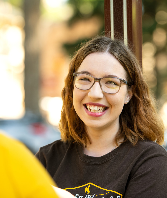Student smiling at the camera while talking to a friend