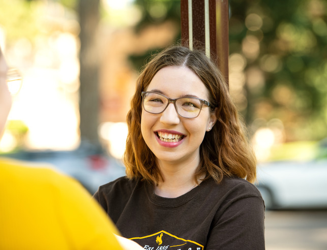 Student smiling at the camera while talking to a friend