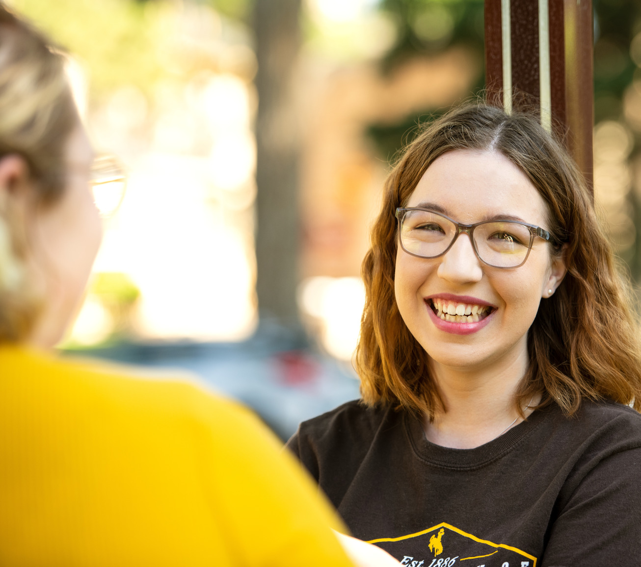 Student smiling at camera while talking to a friend