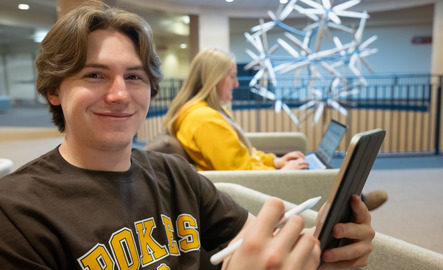 Student smiling for photo while holding a tablet and tablet pen