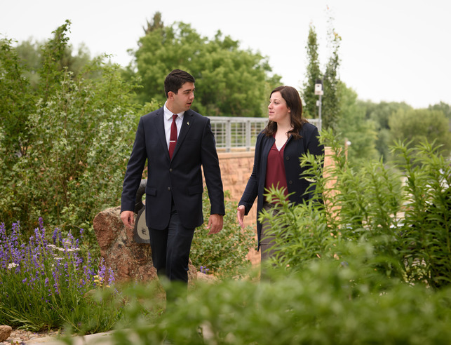 Two people walk together through a garden