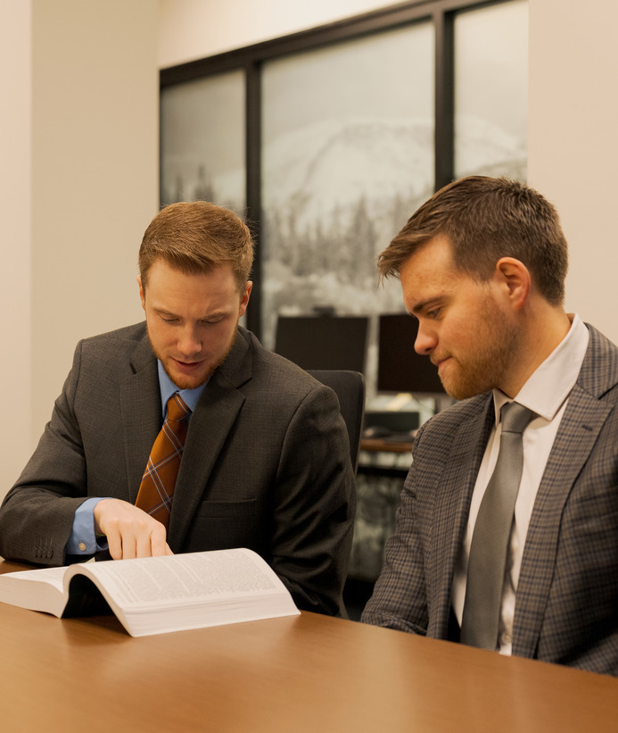 Two people look at a book together in a conference room